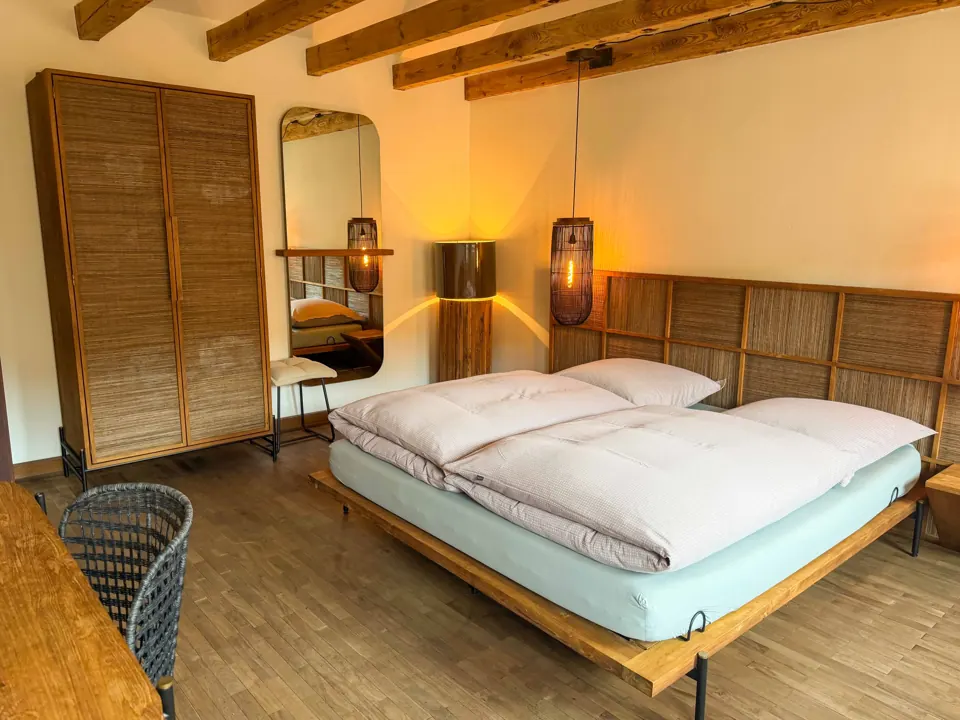 Doppelzimmer mit Holzbalken und warmem Licht im Gästehaus der Auermühle