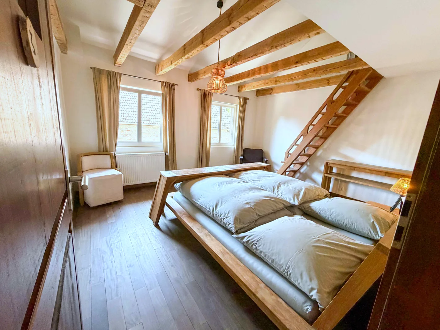 Schlafzimmer unter alten Dachbalken im Gästehaus der Auermühle