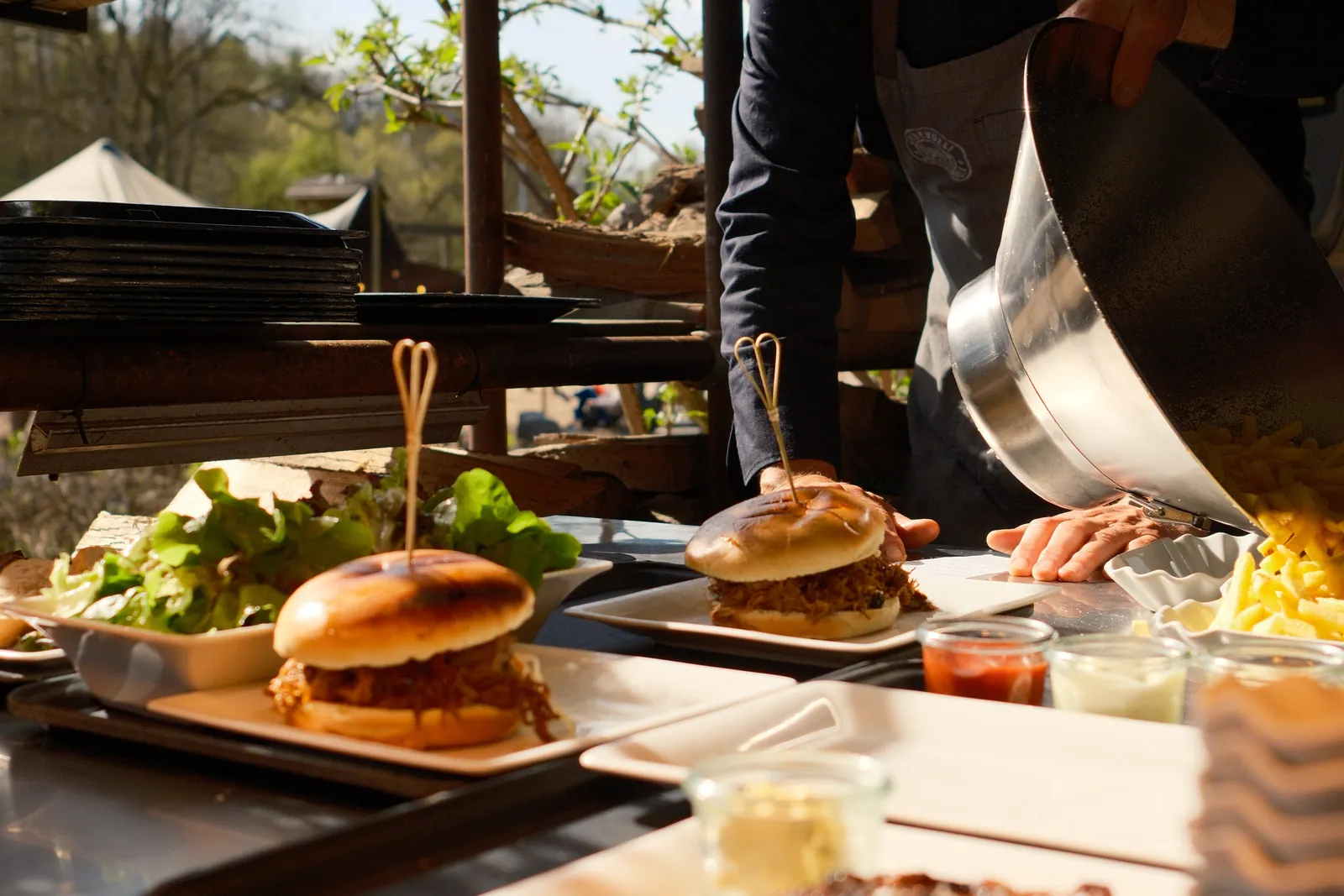 An der Foodstation: Pulled-Pork-Burger werden angerichtet, frische Pommes kommen aus der Schüssel